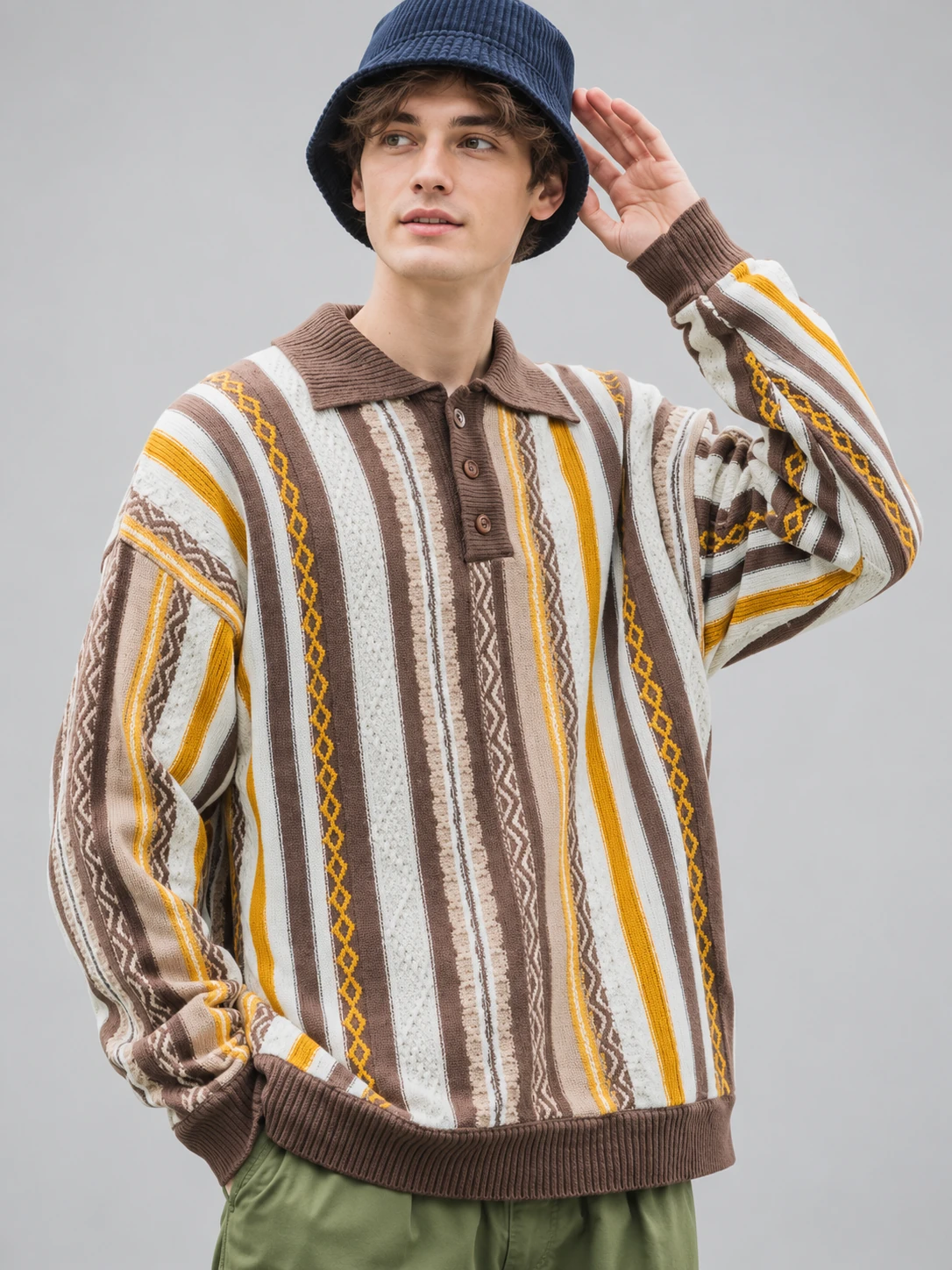 Man wearing a long-sleeve knit polo with a brown collar, short button placket and cream, brown and mustard vertical stripes